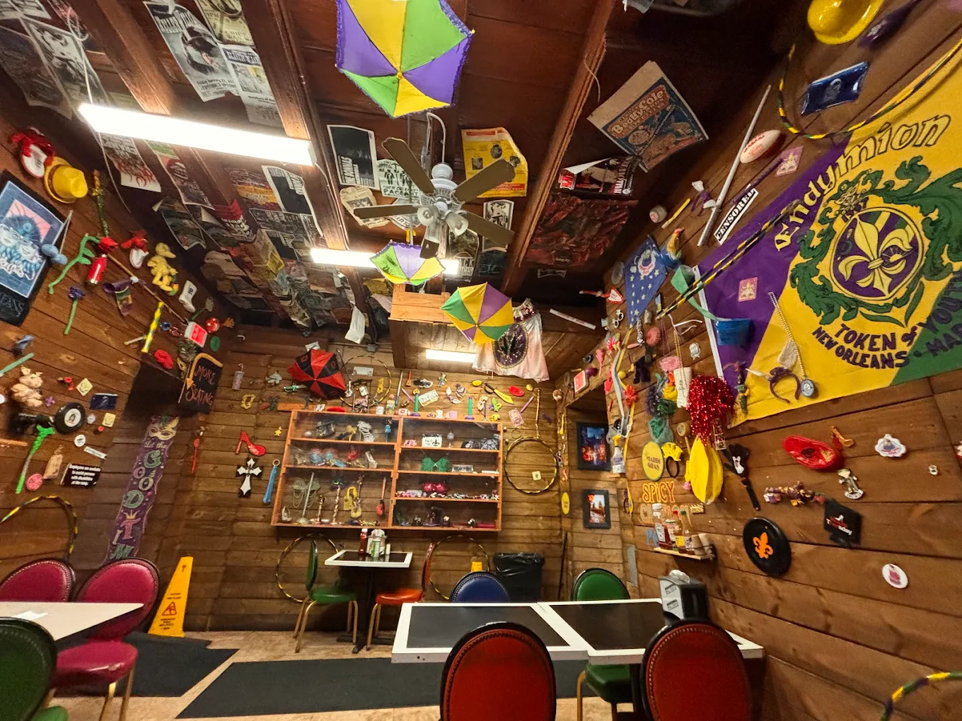 NOLA Poboys interior on Bourbon Street: wood-paneled walls, small tables, and Mardi Gras decor.